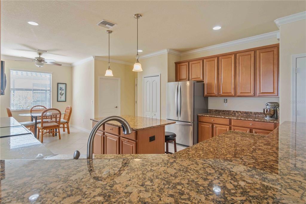 20370 Grazie Place Venice, FL 34293 - Photo 15 of 86 a kitchen with stainless steel appliances granite countertop a stove a sink a dining table and chairs with wooden floor