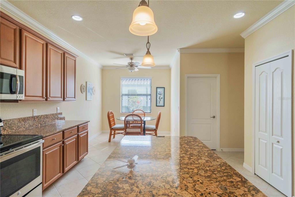 20370 Grazie Place Venice, FL 34293 - Photo 17 of 86 a kitchen with stainless steel appliances granite countertop a stove top oven a sink dishwasher a dining table and chairs with wooden floor