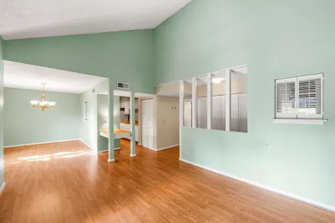 a view of an empty room with wooden floor and a window