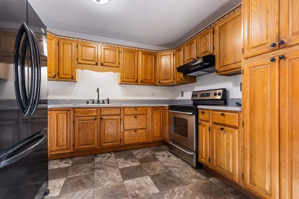 a kitchen with stainless steel appliances granite countertop a stove a sink and a refrigerator with wooden cabinets