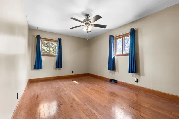 a view of an empty room with window and wooden floor