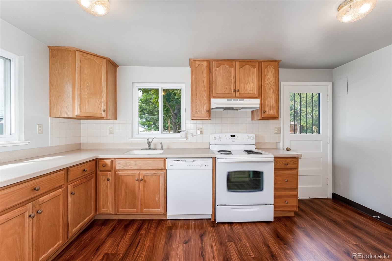2817 Gray Street Wheat Ridge, CO 80214 - Photo 4 of 18 a kitchen with a stove white cabinets and wooden floor