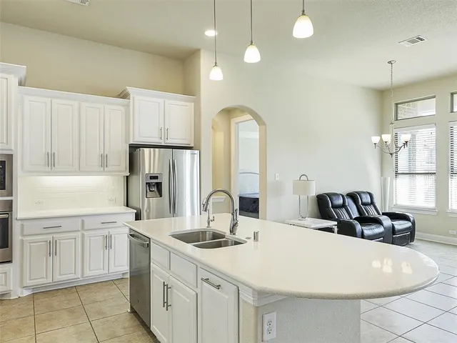 a kitchen with stainless steel appliances a sink a stove a refrigerator and cabinets