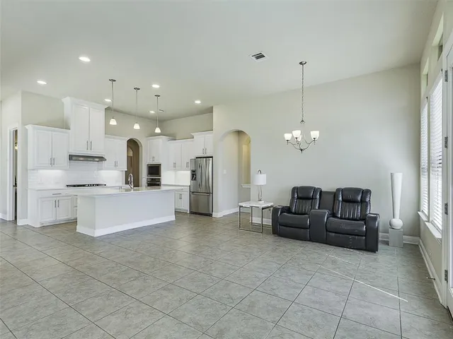 a large white kitchen with stainless steel appliances kitchen island granite countertop a refrigerator a stove a sink and a black granite countertops