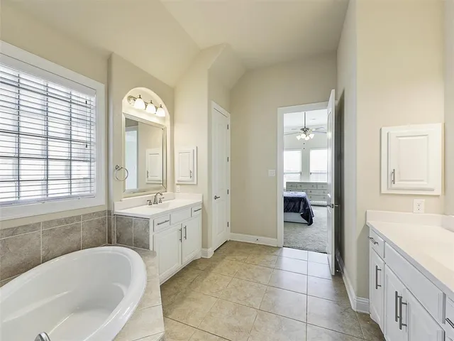 a spacious bathroom with a tub sink and mirror