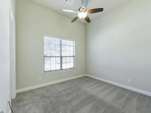an empty room with a window and a fan