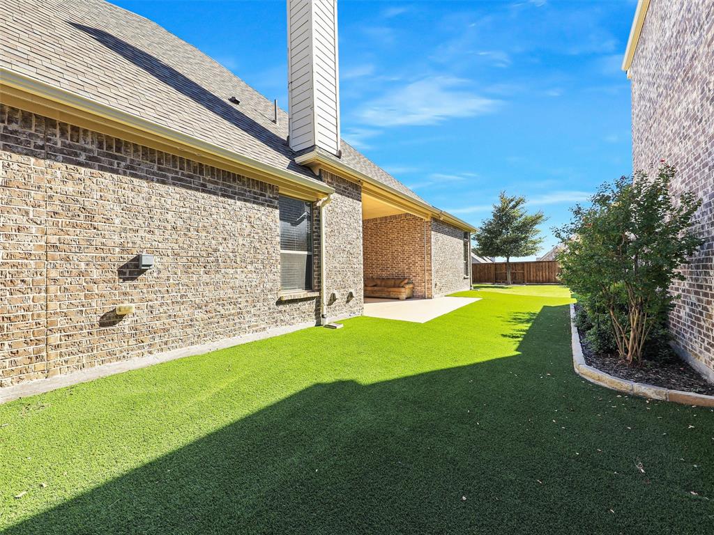 4901 Dolorosa Lane Prosper, TX 75078 - Photo 32 of 37 Turf side yard that leads to large outdoor living area with the fireplace and patio.