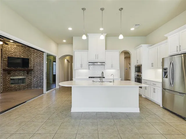 a view of kitchen with stainless steel appliances kitchen island granite countertop a stove a sink a refrigerator and a living room view