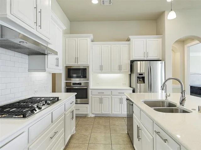 a kitchen with white cabinets and appliances