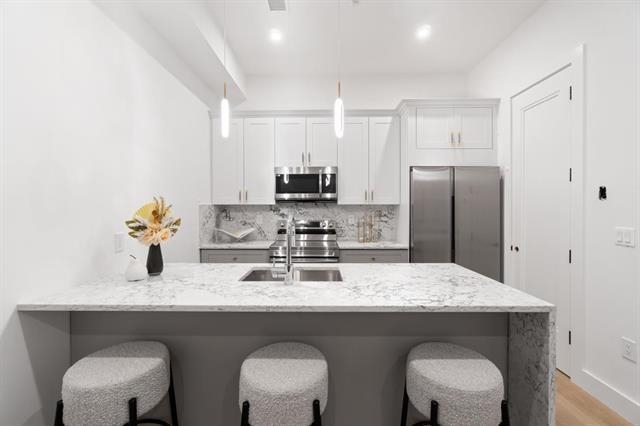 491 Broadway, Unit 402 Bayonne, NJ 07002 - Photo 8 of 20 a kitchen with stainless steel appliances granite countertop a dining table chairs refrigerator and sink