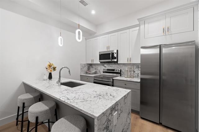 491 Broadway, Unit 402 Bayonne, NJ 07002 - Photo 9 of 20 a kitchen with kitchen island a refrigerator stove microwave and cabinets