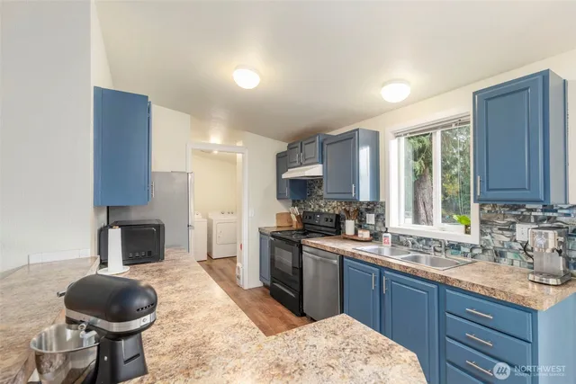 a kitchen with a sink a stove a refrigerator cabinets and a window