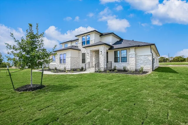 a view of a house with a big yard plants and large trees