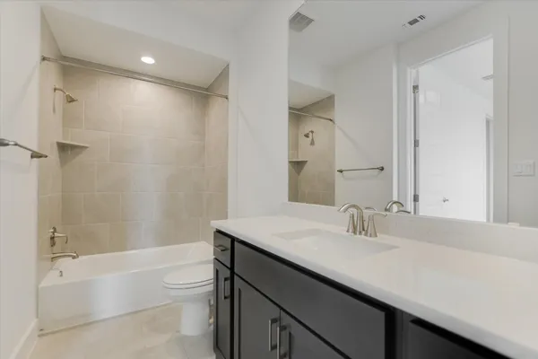a bathroom with a bathtub shower sink vanity and toilet