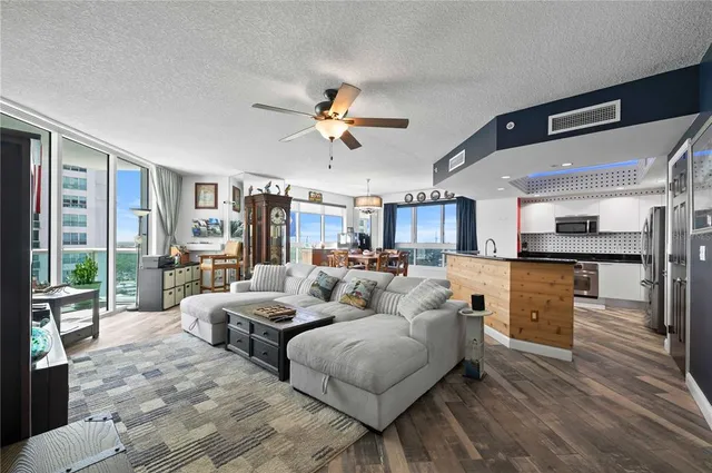 a living room with furniture kitchen view and a large window