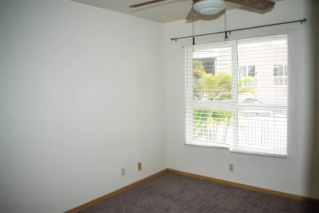 an empty room with a window and a fan
