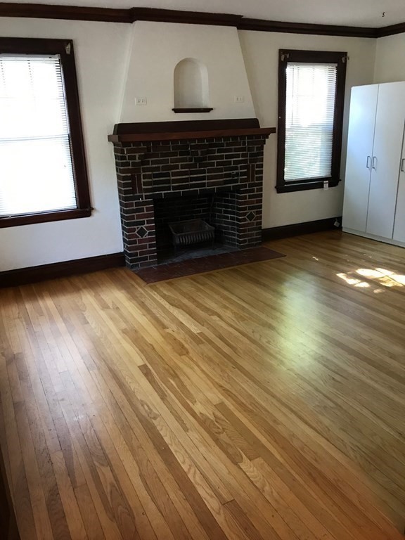 120 Lake Street Boston, MA 02135 - Photo 4 of 28 a view of an empty room with wooden floor and a fireplace