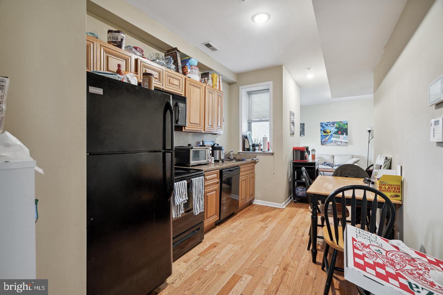 1611 North 17th Street, Unit B Philadelphia, PA 19121 - Photo 7 of 10 a kitchen with stainless steel appliances a refrigerator a stove a sink dishwasher and white cabinets with wooden floor
