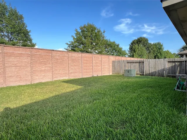 a view of a backyard with a large tree and wooden fence