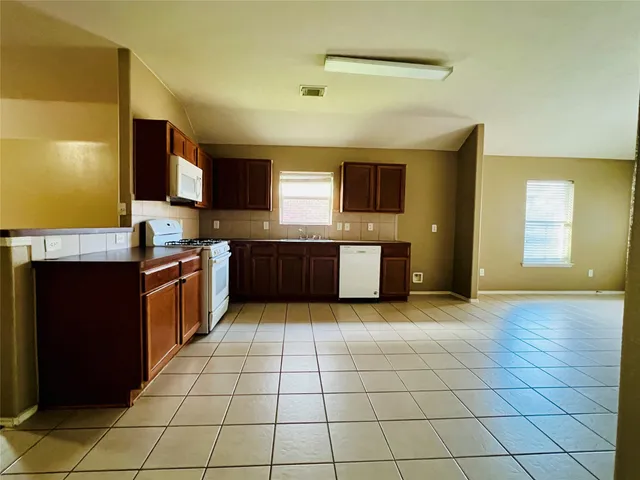 a large kitchen with stainless steel appliances granite countertop a stove a sink and a microwave