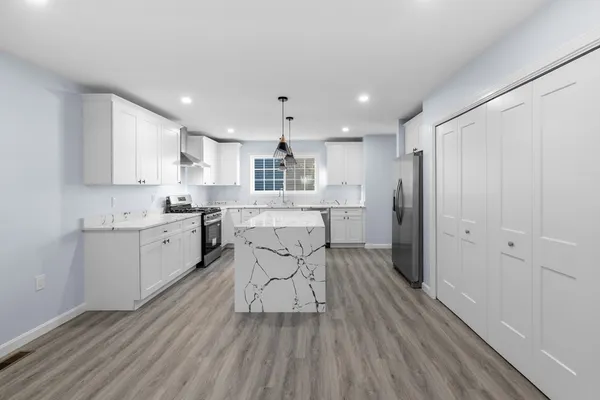 a kitchen with stainless steel appliances kitchen island hardwood floor sink and cabinets