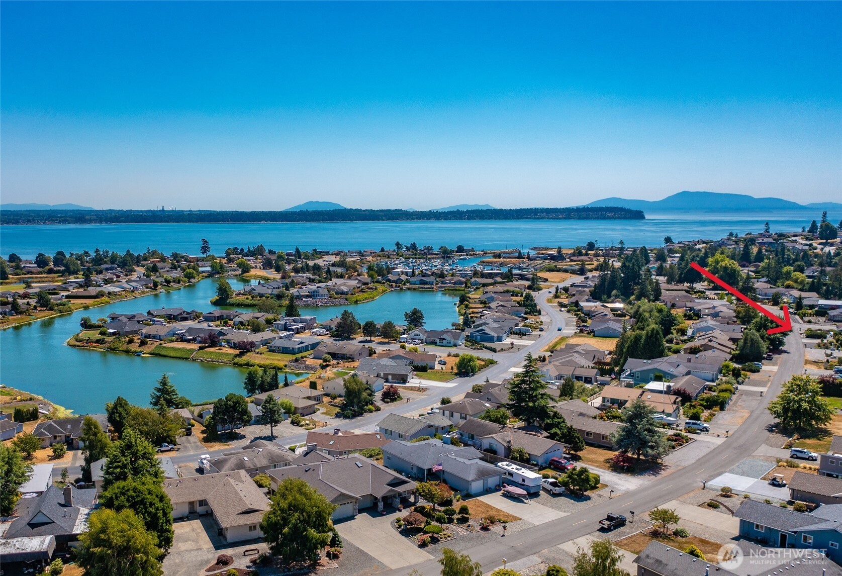 an aerial view of a city with lots of residential buildings and ocean view in back
