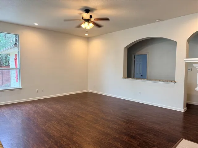 a view of an empty room with a window and wooden floor