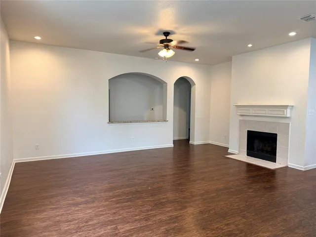 a view of an empty room with wooden floor and a fireplace
