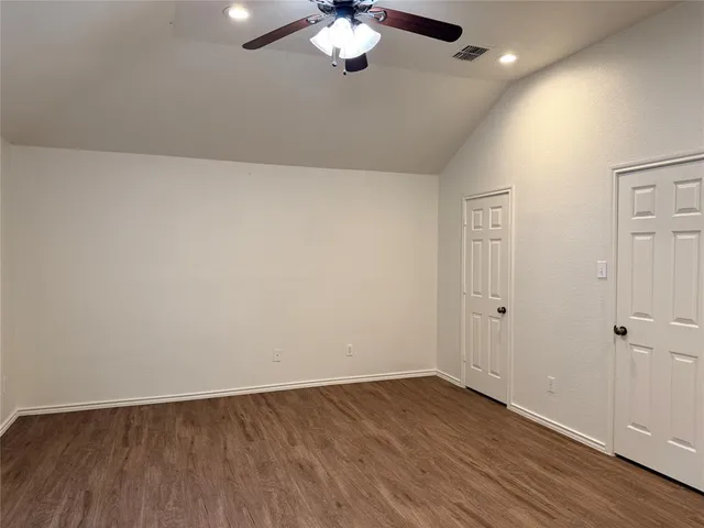 an empty room with wooden floor chandelier fan and windows