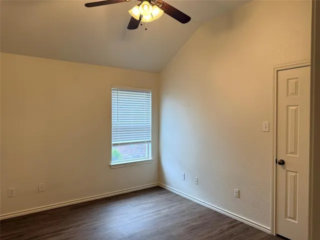 an empty room with wooden floor chandelier fan and windows