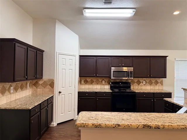 a kitchen with kitchen island granite countertop a refrigerator stove and oven