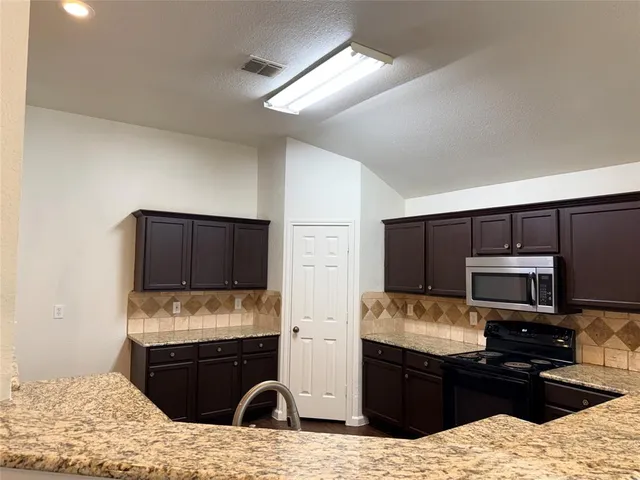 a kitchen with stainless steel appliances granite countertop a stove refrigerator and microwave