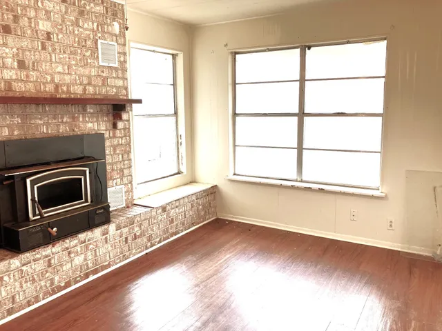 a view of a livingroom with wooden floor a fireplace and windows