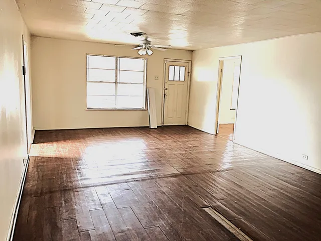 an empty room with wooden floor and windows