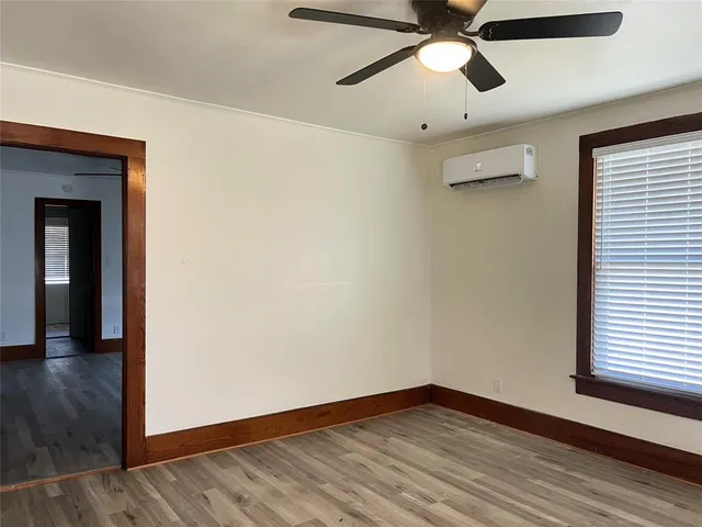 a view of empty room with wooden floor and fan
