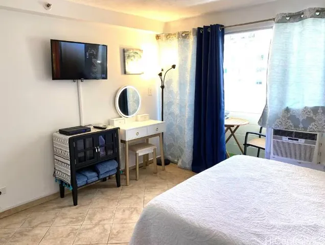 a bedroom with a bed a flat screen tv and next to a window