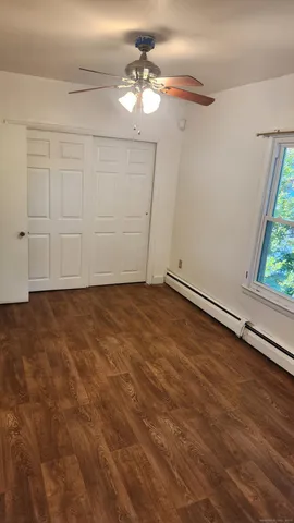 an empty room with wooden floor fan and windows