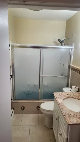 a bathroom with a granite countertop sink a toilet and shower