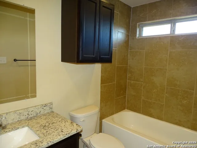a bathroom with a granite countertop bathtub shower sink and toilet