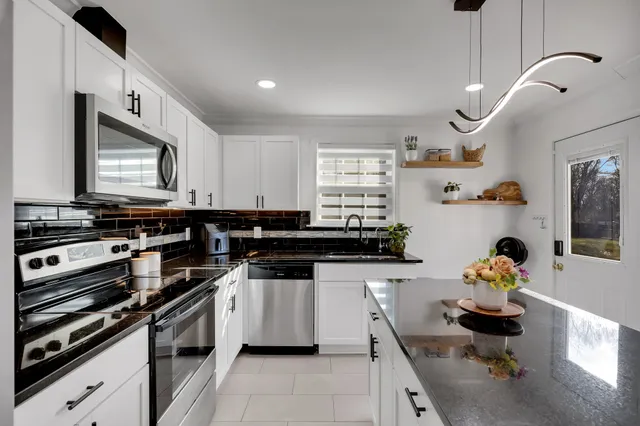 a kitchen with stainless steel appliances a stove a sink cabinets and a window