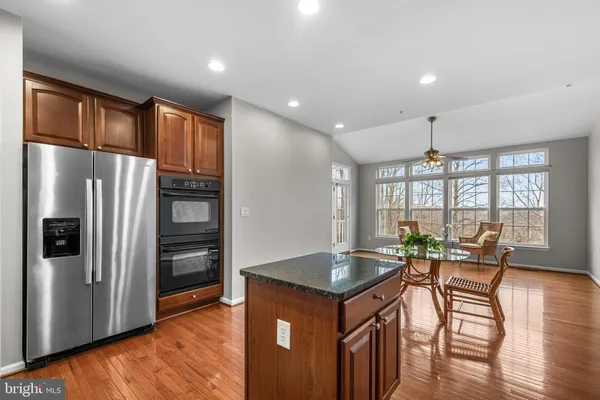 a open kitchen with stainless steel appliances granite countertop a refrigerator a stove and a dining table with wooden floor