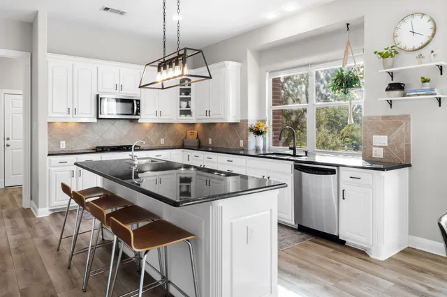 a kitchen with stainless steel appliances granite countertop a sink a stove a refrigerator and island