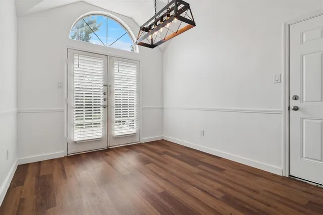 an empty room with wooden floor closet and windows