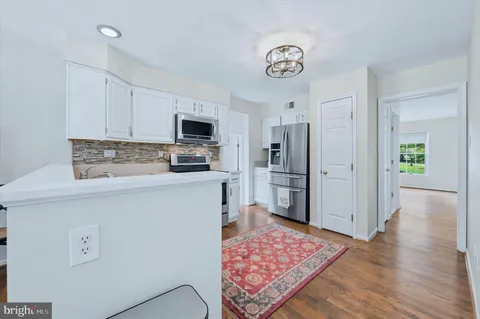 a kitchen with stainless steel appliances granite countertop a refrigerator oven a sink dishwasher and a refrigerator with wooden floor