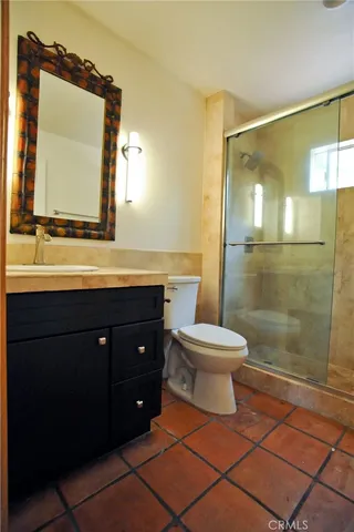 a bathroom with a toilet a sink a mirror and shower