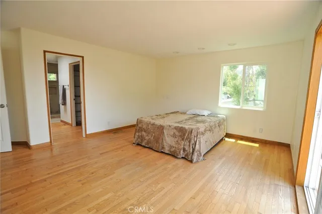 a spacious bedroom with a bed and wooden floor
