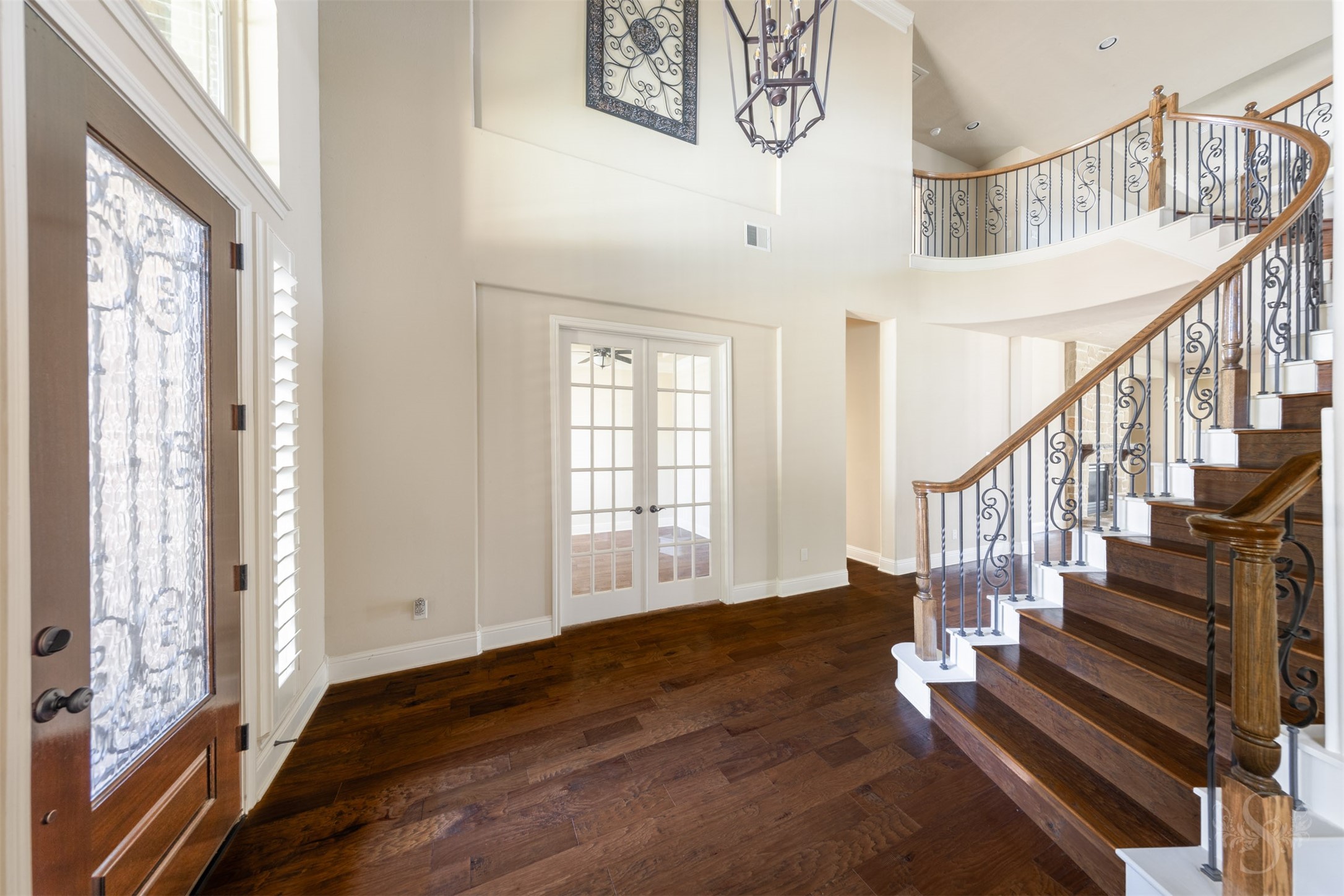 5803 Mustang Ridge Lane Fulshear, TX 77441 - Photo 5 of 48 Sweeping curved staircase with decorative iron balusters and rich wood steps creates a dramatic focal point within the grand 2 story entry. Soaring ceilings and elegant architectural details enhance the home’s impressive open feel.