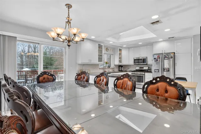 a kitchen with stainless steel appliances granite countertop a stove a sink dishwasher a dining table and chairs with wooden floor