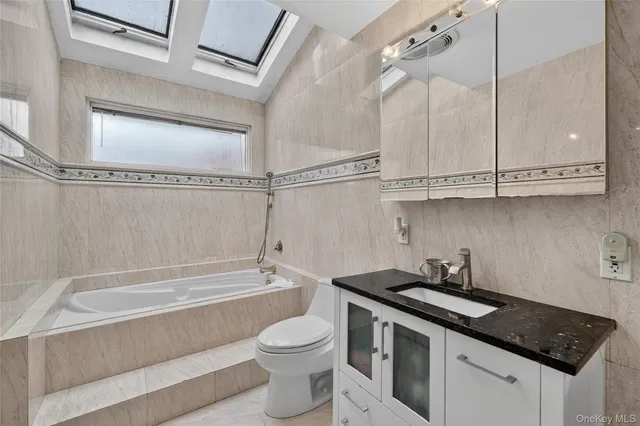 a bathroom with a granite countertop sink a toilet and bathtub