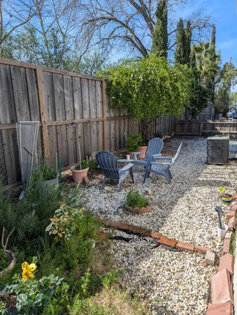 a backyard of a house with table and chairs under an umbrella